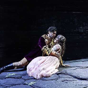 Szenenbild Faust:Ein Mann und eine Frau sitzen auf dem Boden und umarmen sich