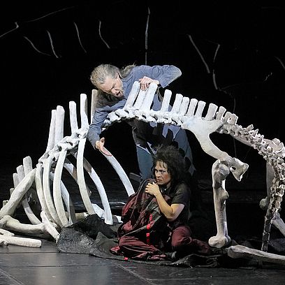 Szene Parsifal: Ein gro&szlig;es Tierskelett, zwei Menschen darunter