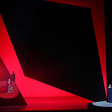 Szene Elektra: Drei Personen auf der Bühne, rotes Bühnenbild