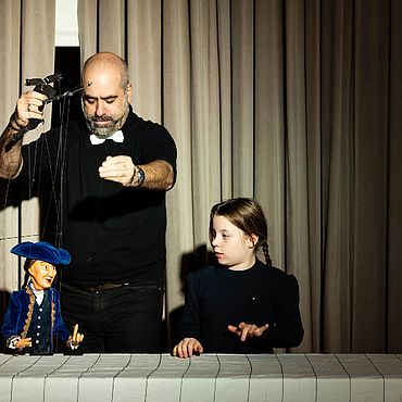 Szene aus "Carissima Sorellina" mit Puppenspieler und M&auml;dchen