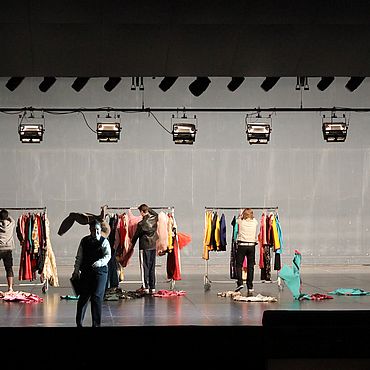 Szenenbild Ariadne auf Naxos: Personen stehen vor Kleiderst&auml;ndern