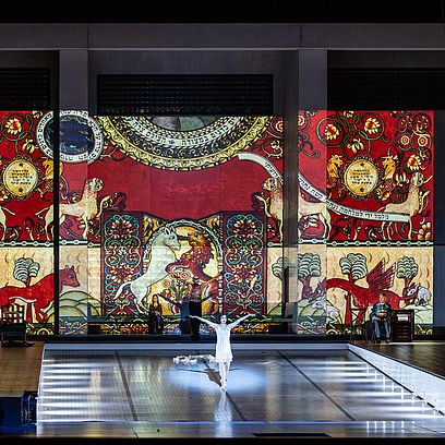 Szenenbild Salome: Salome in einem wei&szlig;en Unterkleid in der Mitte der Bibliothek; im Hintergrund die Projektion einer mittelalterlichen Malerei