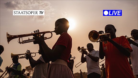 People playing brass instruments before a sunset