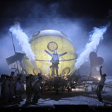 Szenenbild L&rsquo;elisir d&rsquo;amore: Eine futuristische kugelf&ouml;rmige Maschine umgeben von Rauch