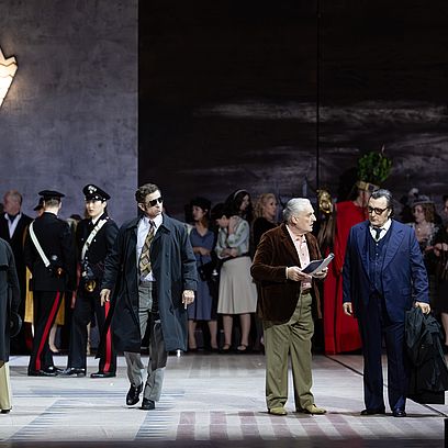 Szene aus Tosca: Eine Gruppe von Menschen auf der B&uuml;hne, zwei M&auml;nner diskutieren