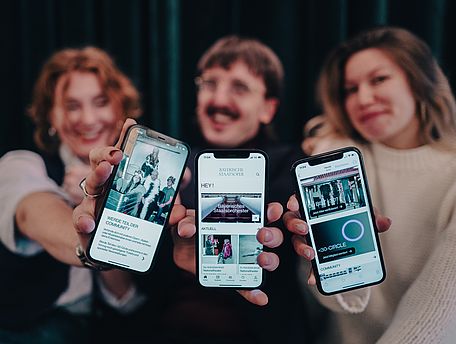 Drei Menschen halten Handy mit App in die Kamera