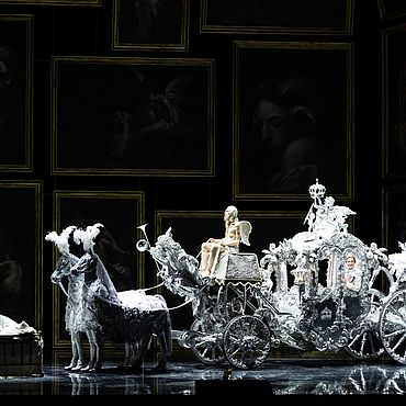 Szenenbild Der Rosenkavalier: Eine pr&auml;chtige silberfarbene Kutsche gezogen von zwei Pferden, ein Engel als Kutscher
