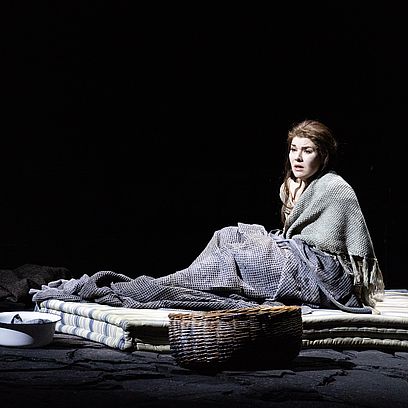Szenenbild Faust: Marguerite sitzt alleine auf einer Matratze am Boden 